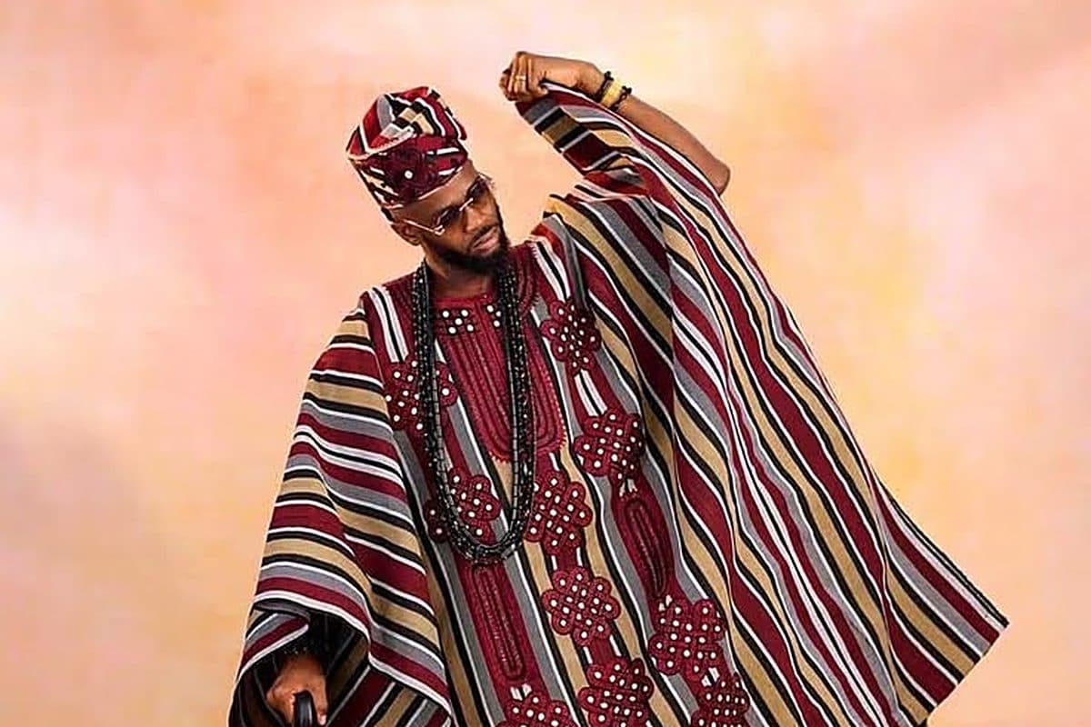 A gentleman in a fully tailored three-piece Asooke agbada with matching fila cap and beaded accessories